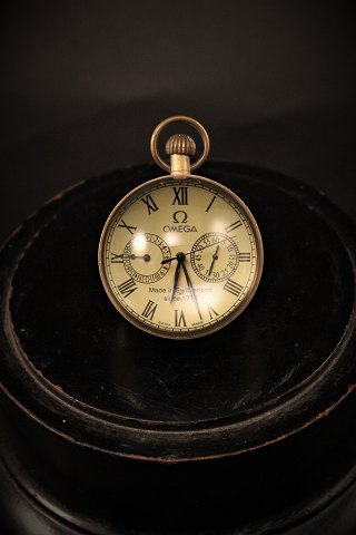 Gammelt Omega bord ur i form af glaskugle montage af messing , med hvid urskive med sorte romertal og mekanisk urværk.