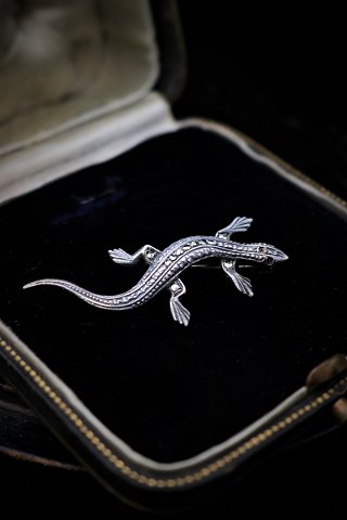 Gammel broche i sølv i form af salamander med masser af små skinnende magasiter. Måler: L:5cm.